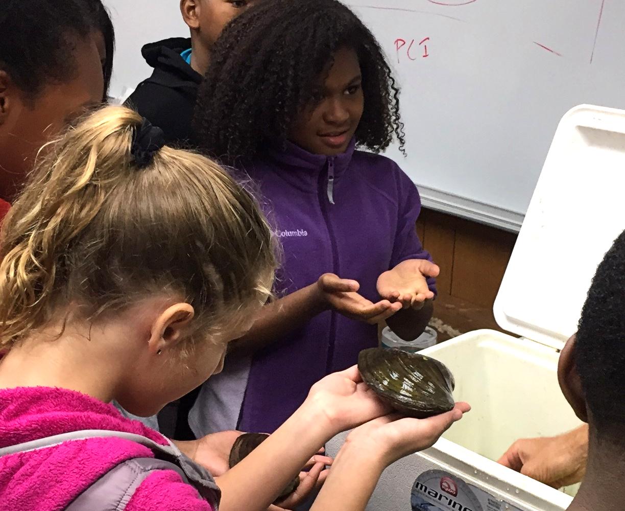 students holding mussels at a lab visit