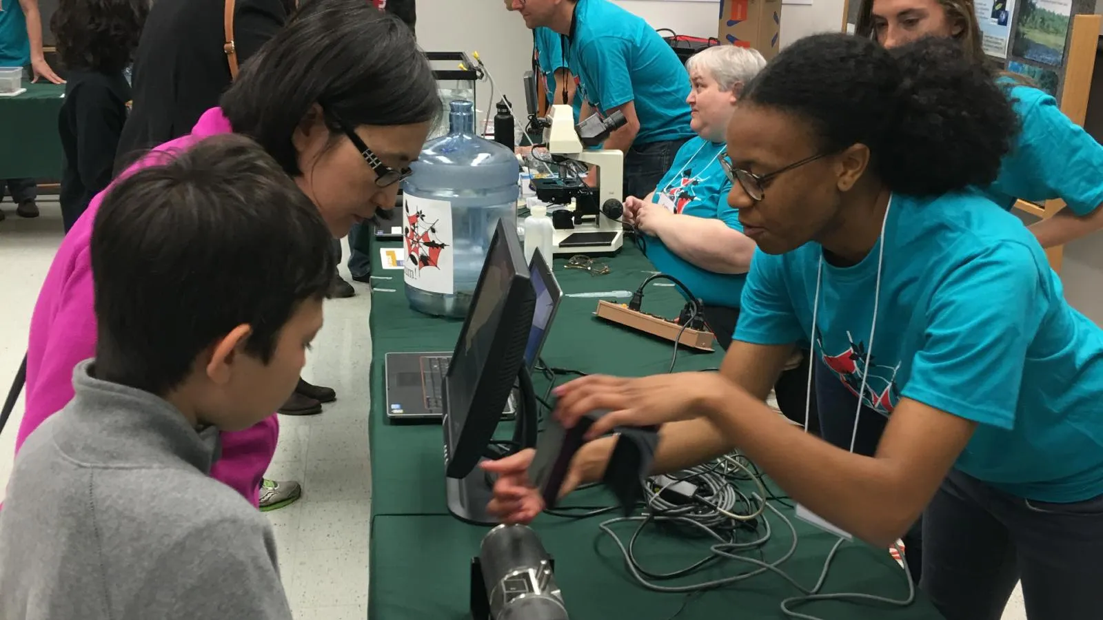 AEL student showing field equipment to community members at MBD
