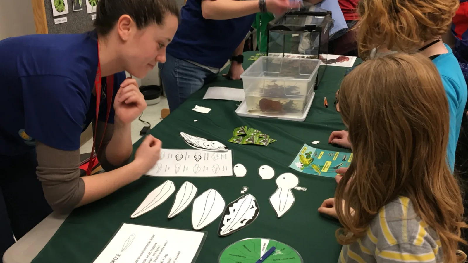 AEL student explaining tadpoles to kids at community outreach event MBD