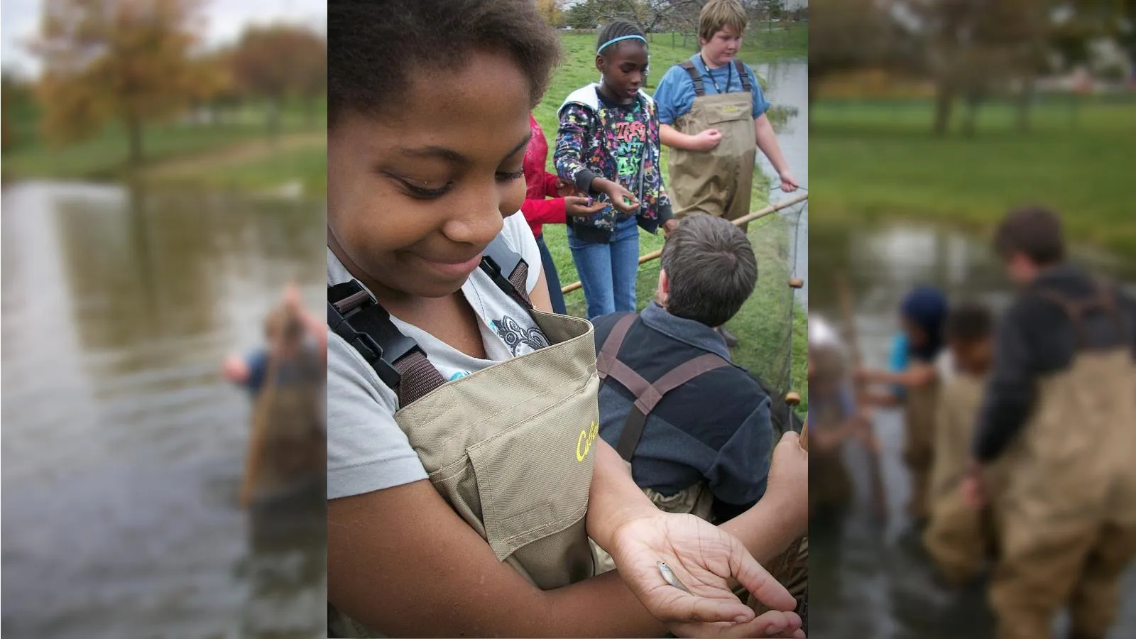 Girl smiling at small fish in her hand