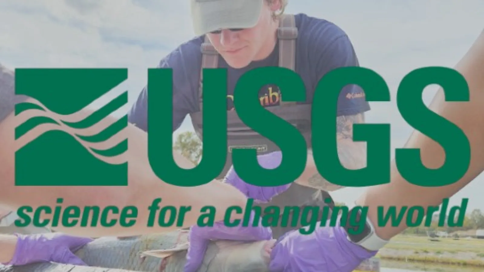 USGS Logo over James Dowling doing fish surgery