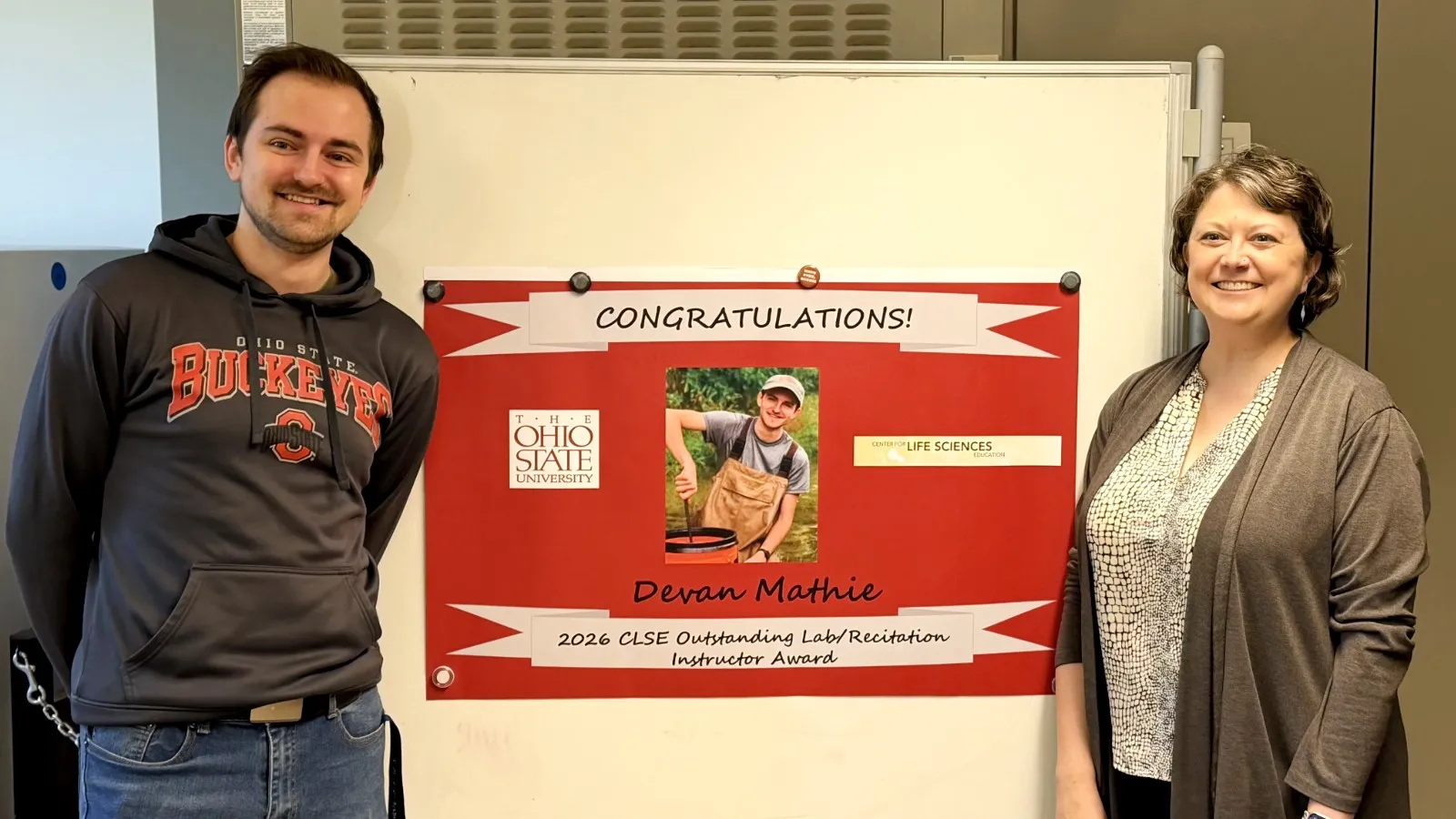 Devan Mathie posing next to his CLSE outstanding instructor sign