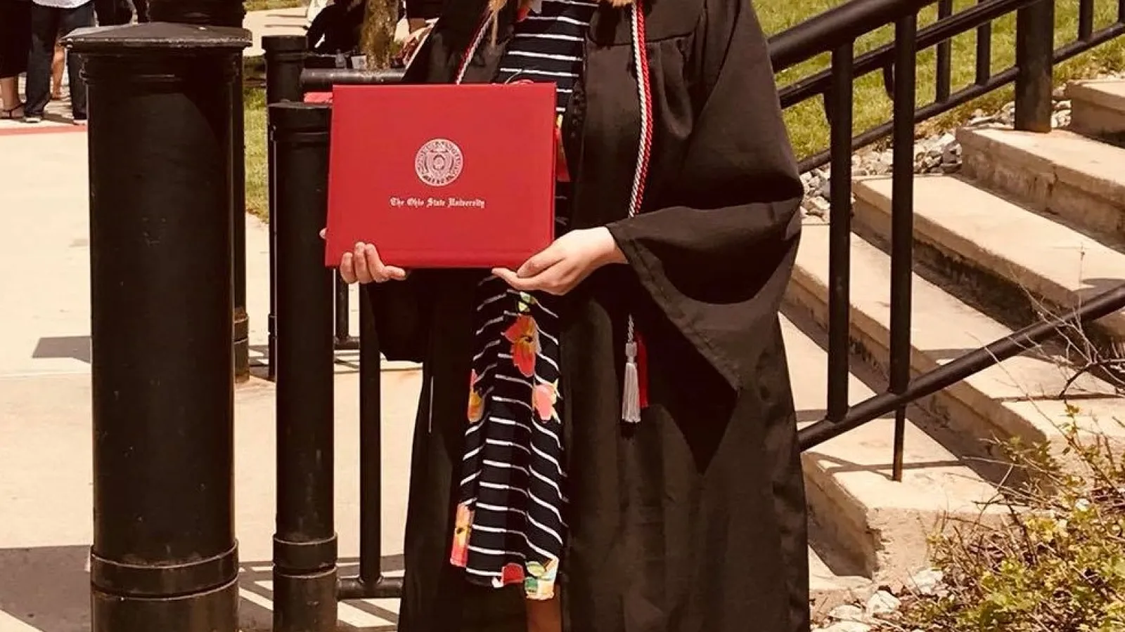 Taylor Brown holds her diploma and wears her graduation robes at 2018's spring commencement