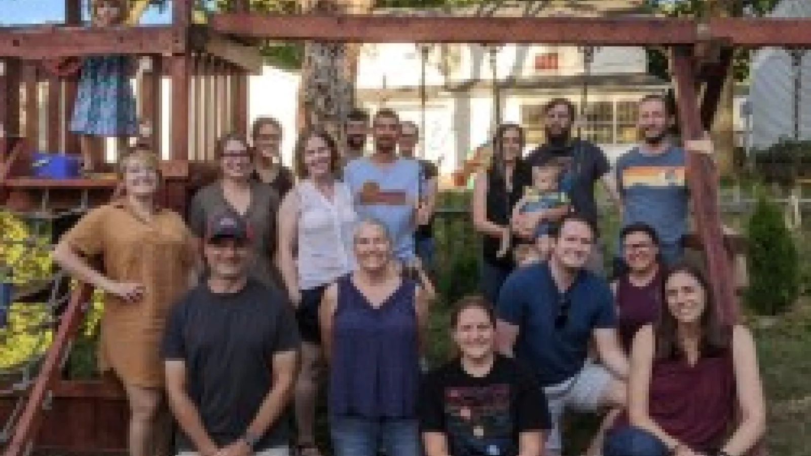 Group photo of AEL members in front of a backyard play set