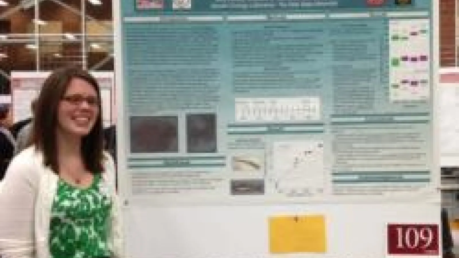 Student standing next to their poster
