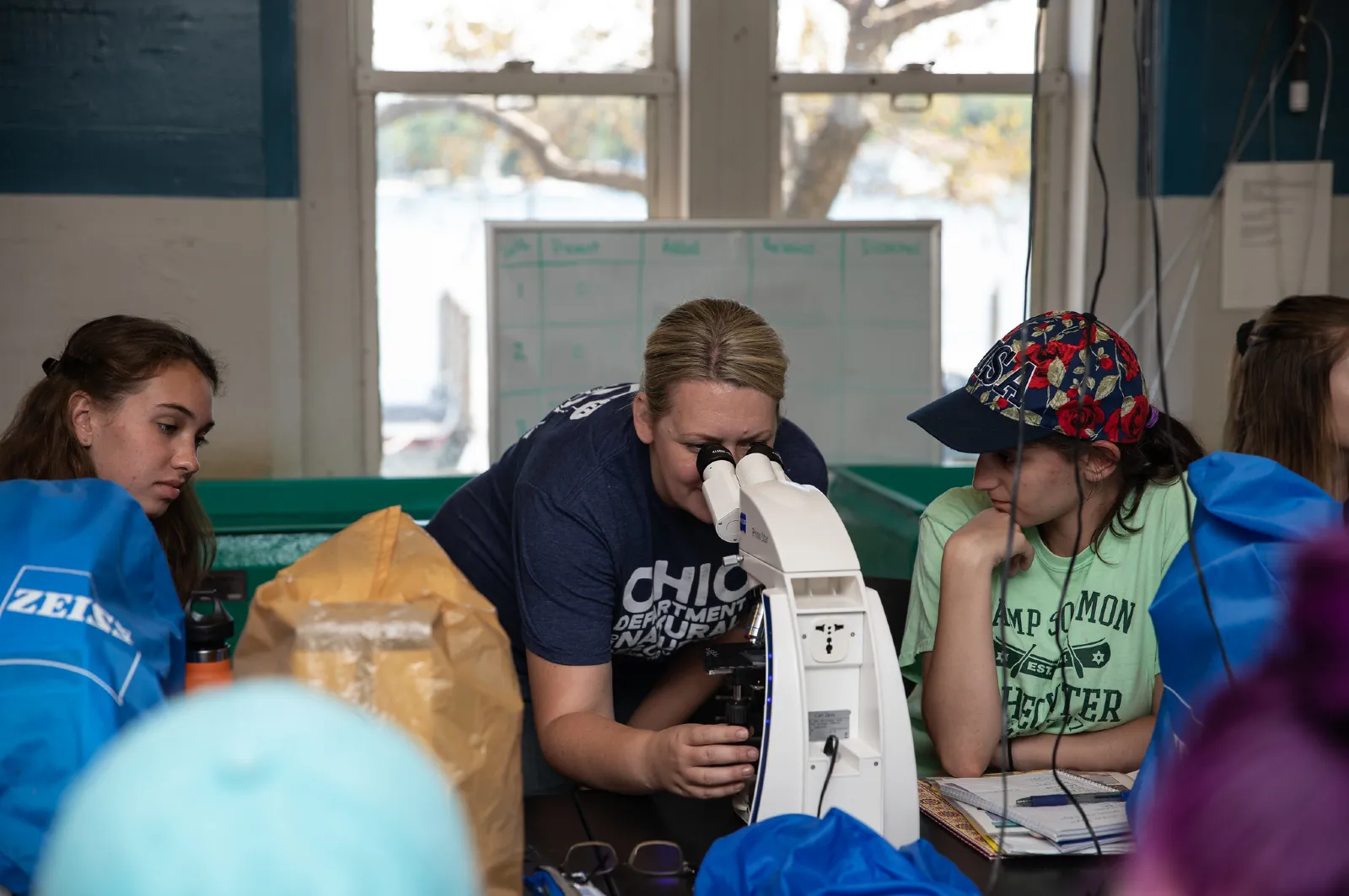 Kristen Fussell showing two students how to use a microscope at Stone Lab