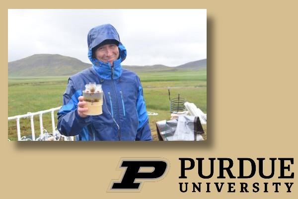 Jim Hood in the field next to Purdue University Logo