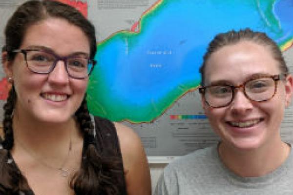 Rachel Finigan and Hannah Moore stand in front of a map of Lake Erie