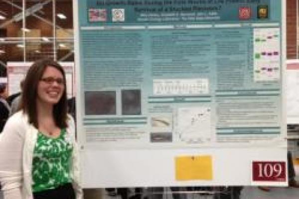 Student standing next to their poster