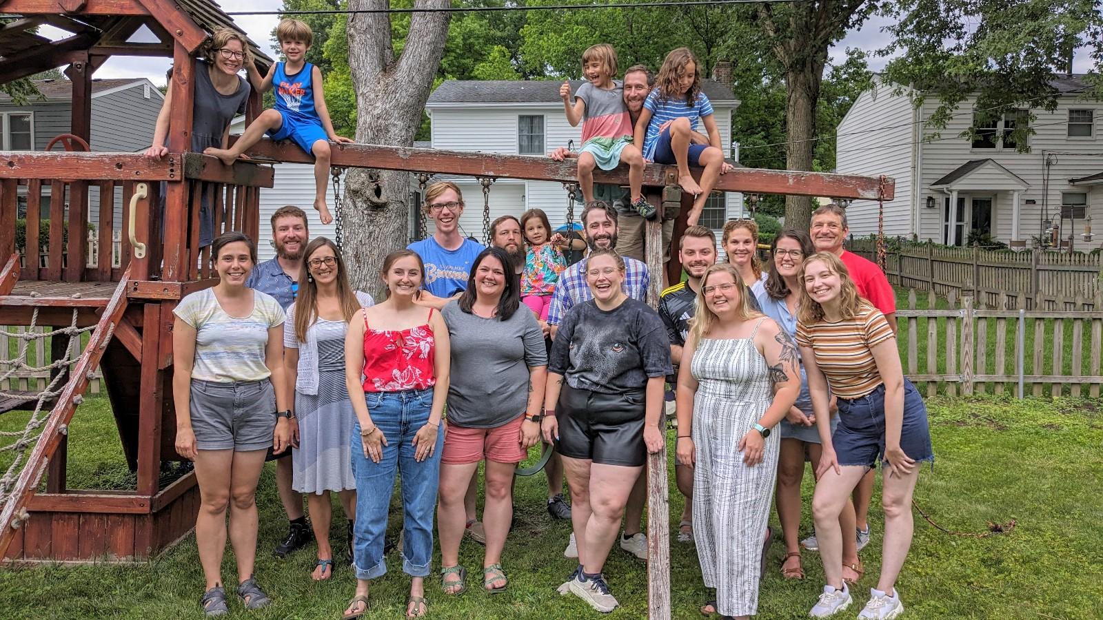 Group photo of AELers and families in front of a backyard swingset