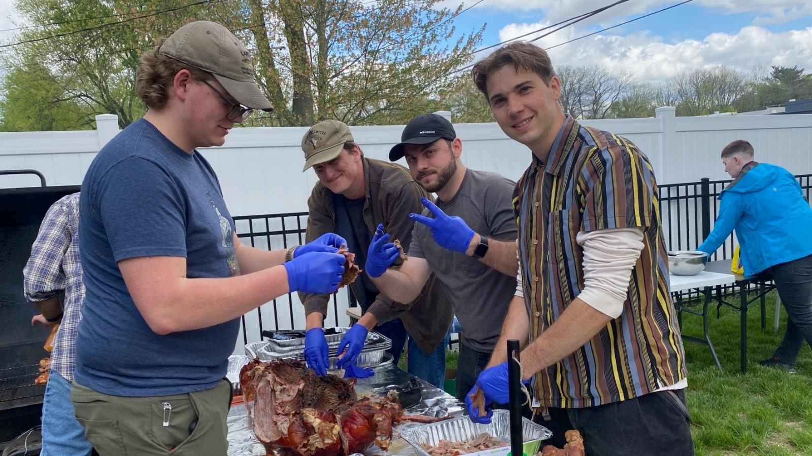 Jacob, Sawyer, Matt, and Neil processing the cooked pig