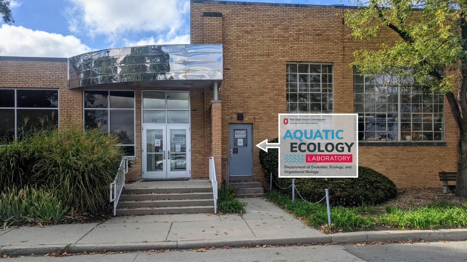 The Research Center building viewed from the driveway with the AEL logo in a arrow box pointing toward the entrance door.